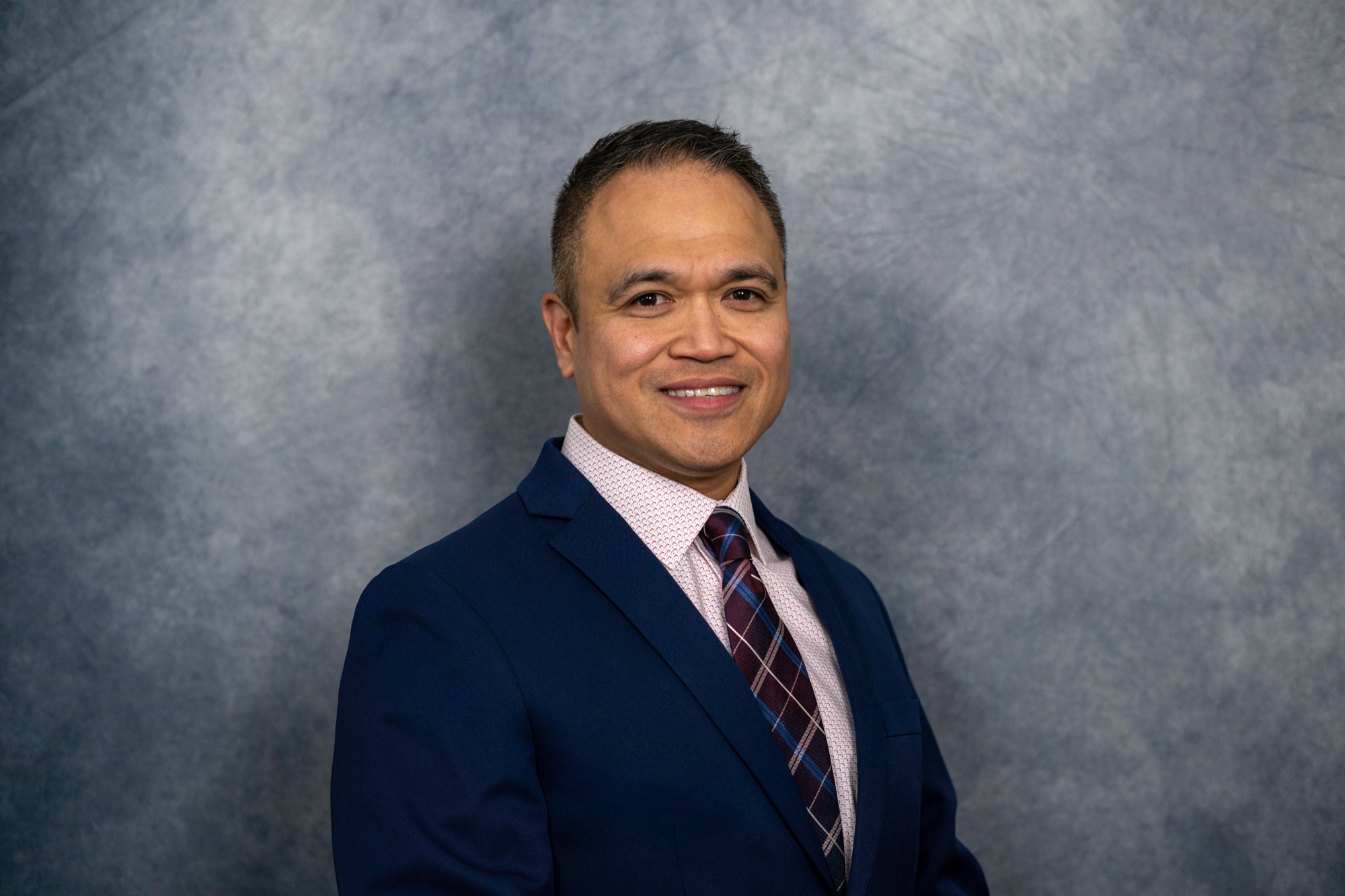 Professional on-site headshot of a physical therapist in a blue suit